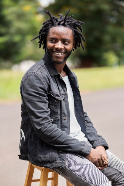 Portret van een jonge man met afro-dreadlocks en jas