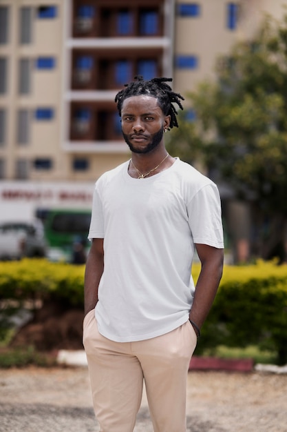 Portret van een jonge man met afro-dreadlocks en wit t-shirt buitenshuis