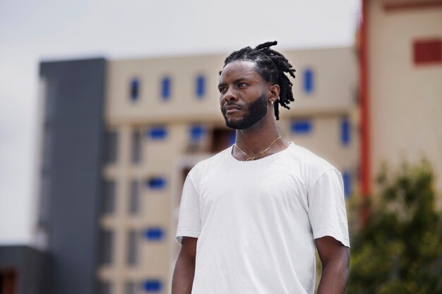 Portret van een jonge man met afro-dreadlocks en wit t-shirt buitenshuis