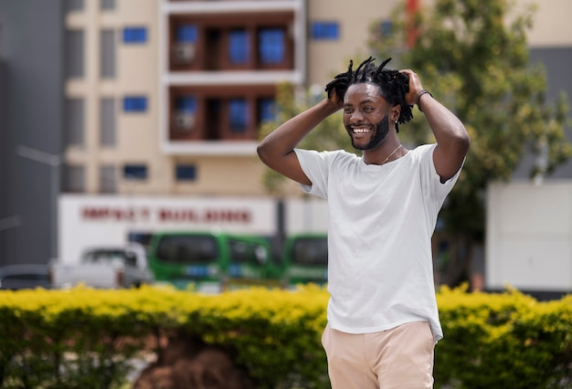 Portret van een jonge man met afro-dreadlocks en wit t-shirt buitenshuis