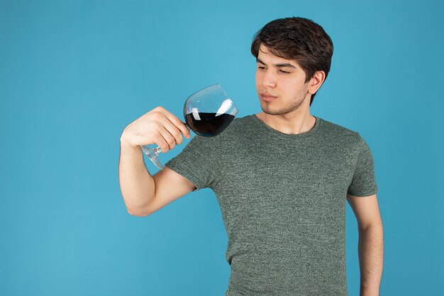 Portret van een jonge man met een glas wijn tegen blauw.