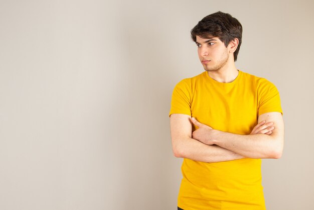 Portret van een jonge man met gekruiste armen tegen grijs.