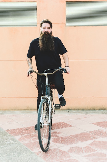 Gratis foto portret van een jonge man met lange baard op de fiets