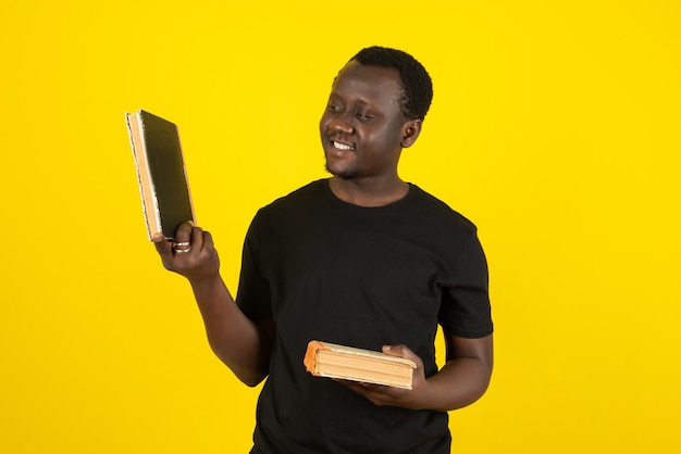 Portret van een jonge man model met boeken tegen gele muur