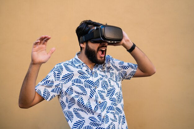 Portret van een jonge man spelen met VR-headset bril van virtual reality tegen gele ruimte. VR-headset bril apparaat. Technologie concept.