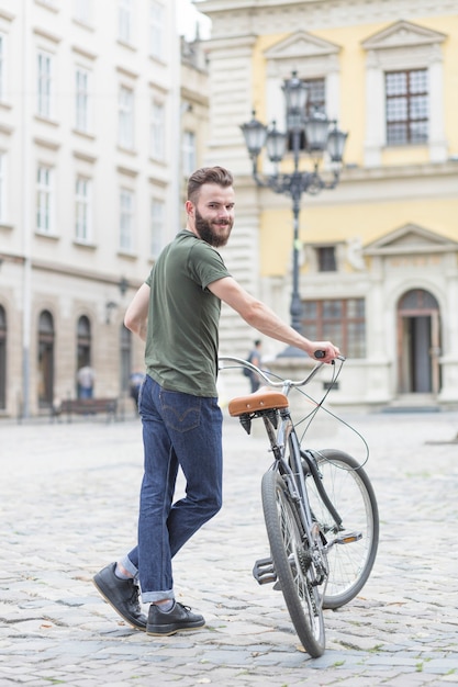 Portret van een jonge mannelijke fietser met zijn fiets