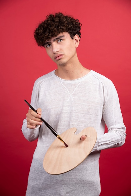 Portret van een jonge mannelijke kunstenaar met palet en borstels.