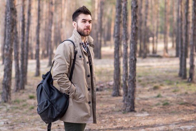 Portret van een jonge mannelijke rugzak van de reizigersholding op zijn schouder in het bos