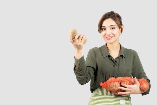 Portret van een jonge mooie boer vrouw met aardappelen in zak. hoge kwaliteit foto