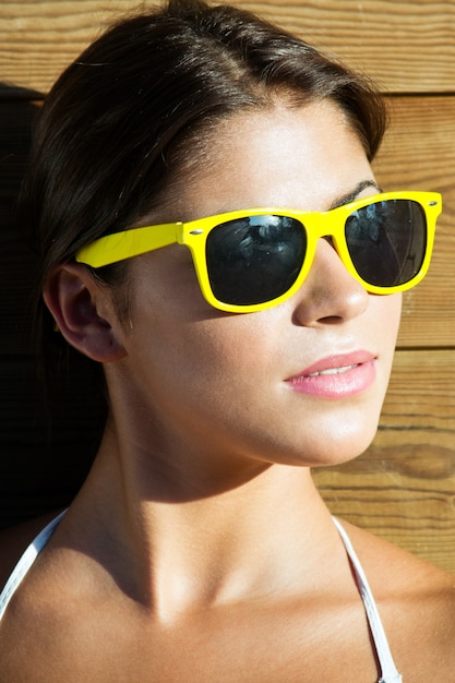 Portret van een jonge mooie vrouw in een park met gele zonnebril