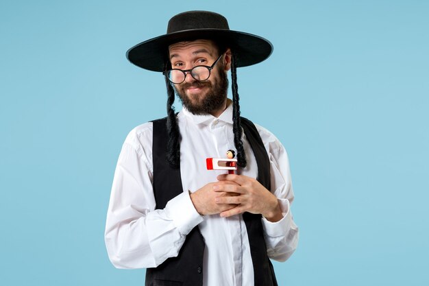 Portret van een jonge orthodoxe joodse man met houten grager-ratel tijdens festival Purim.