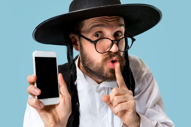 Portret van een jonge orthodoxe joodse man met mobiele telefoon in de studio