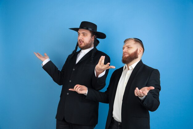 Portret van een jonge orthodoxe Joodse mannen geïsoleerd op blauwe studio