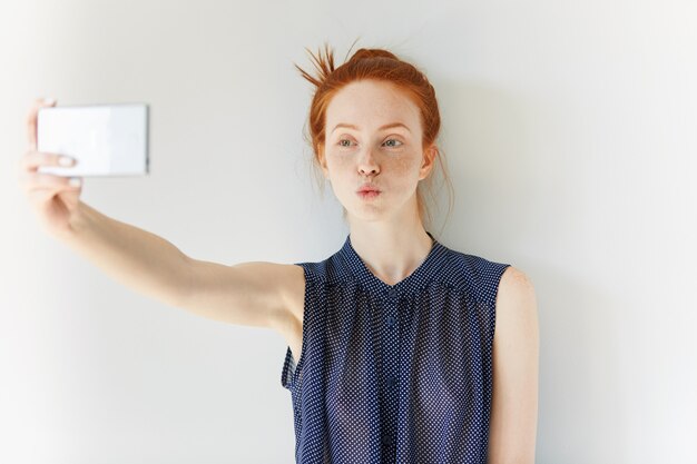 Portret van een jonge roodharige vrouw die selfie