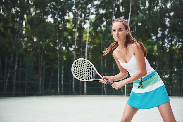 Portret van een jonge tennisser die zich klaar voor een service bevindt.