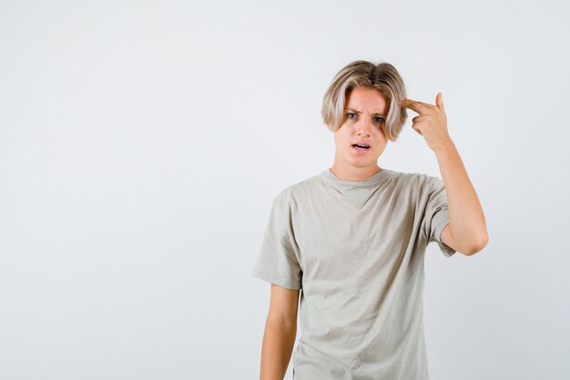 Portret van een jonge tienerjongen die een zelfmoordgebaar in een t-shirt toont en er nerveus vooraanzicht uitziet