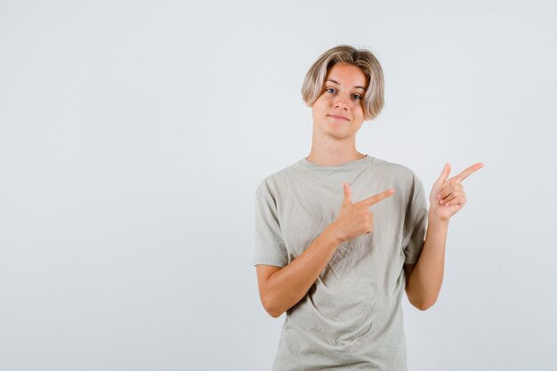 Portret van een jonge tienerjongen die naar de rechterbovenhoek in een t-shirt wijst en er vrolijk vooraanzicht uitziet