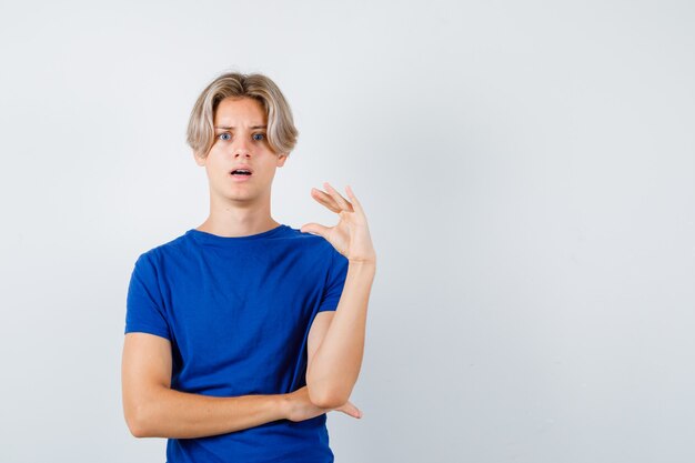 Portret van een jonge tienerjongen met een klein bordje in een blauw t-shirt en een geschokt vooraanzicht