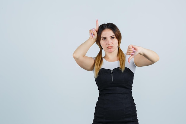 Portret van een jonge vrouw die duimen naar beneden laat zien en er ontevreden uitziet