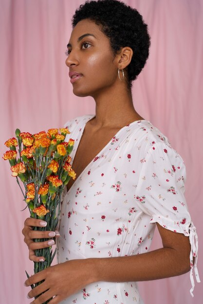 Portret van een jonge vrouw die een chique boho-jurk draagt tussen de bloemen