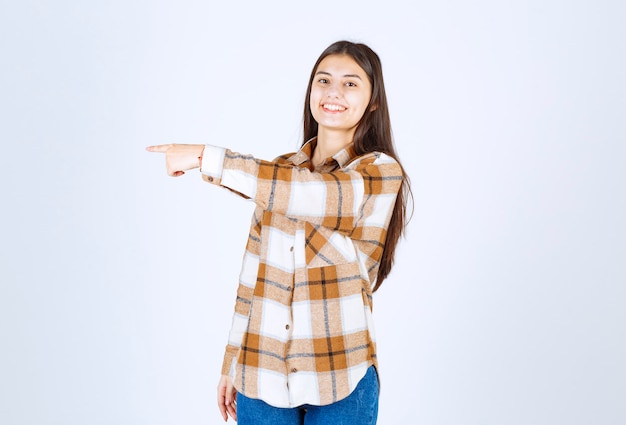 Portret van een jonge vrouw die gelukkig lacht op een witte muur.