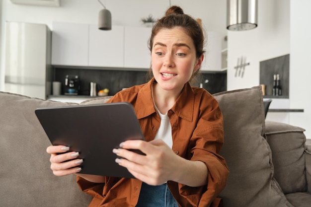 Gratis foto portret van een jonge vrouw die gestresst en gespannen kijkt bij een digitale tablet die video's van moeilijk niveau speelt