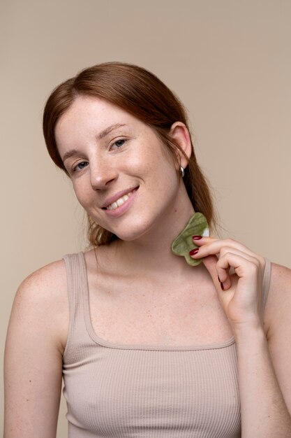 Portret van een jonge vrouw die haar nek masseert met een gua sha