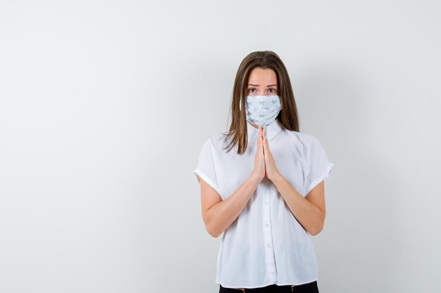 Portret van een jonge vrouw die handen vasthoudt in een biddend gebaar