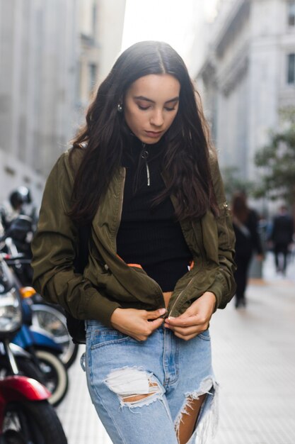 Portret van een jonge vrouw die het jasje op de straat snijdt