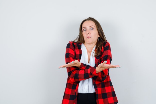 Portret van een jonge vrouw die hulpeloos gebaar toont in vrijetijdskleding en er geen idee van vooraanzicht uitziet