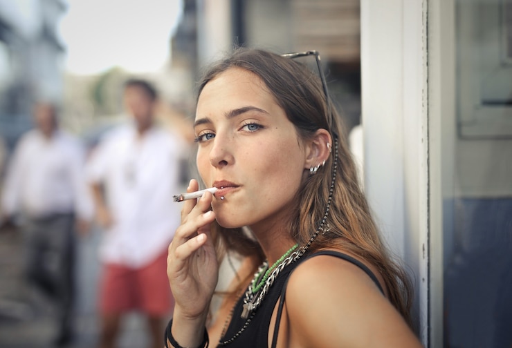Gratis Foto portret van een jonge vrouw die in de straat rookt