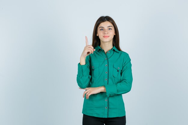 Portret van een jonge vrouw die in groen overhemd benadrukt en vrolijk vooraanzicht kijkt
