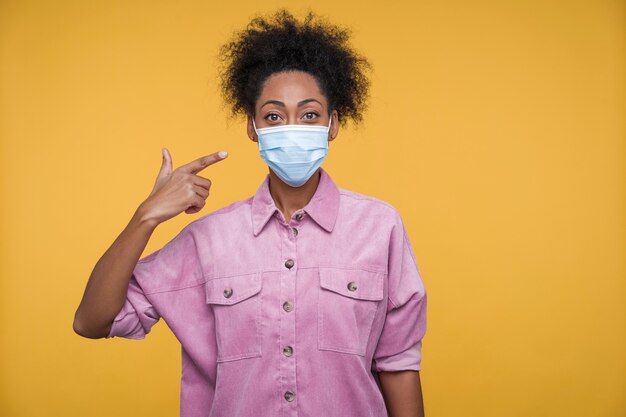 Portret van een jonge vrouw die naar haar medische masker wijst