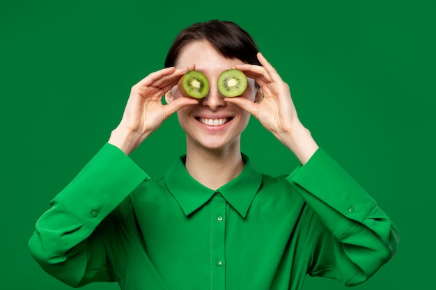 Portret van een jonge vrouw die ogen bedekt met kiwi