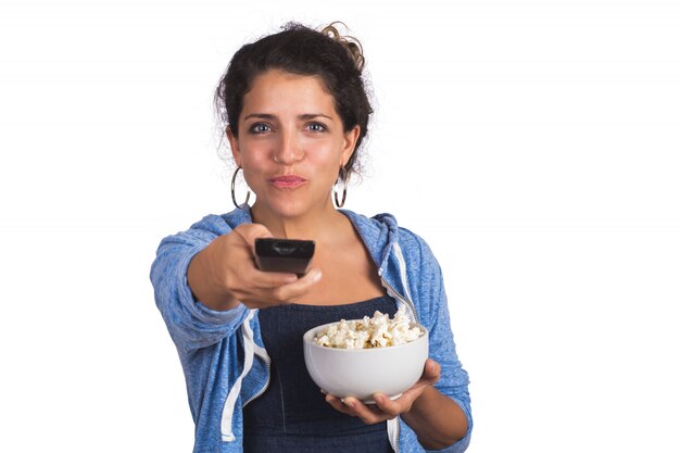 Portret van een jonge vrouw die op een film let en popcorn eet op studio.
