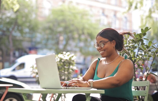 portret van een jonge vrouw die op een terras zit met een computer