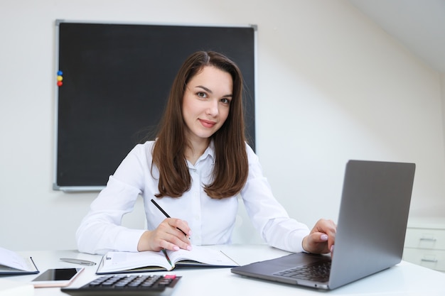 Portret van een jonge vrouw die op haar laptop op kantoor werkt