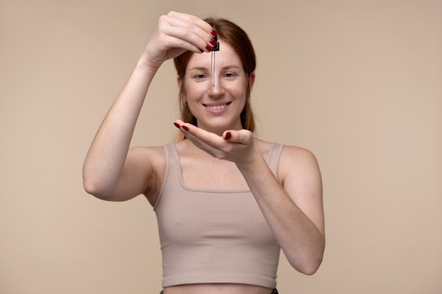 Portret van een jonge vrouw die serum op haar hand giet