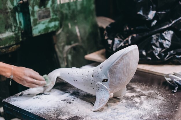 Portret van een jonge vrouw die van favoriete baan in workshop geniet. pottenbakker werkt zorgvuldig aan de keramische walvis