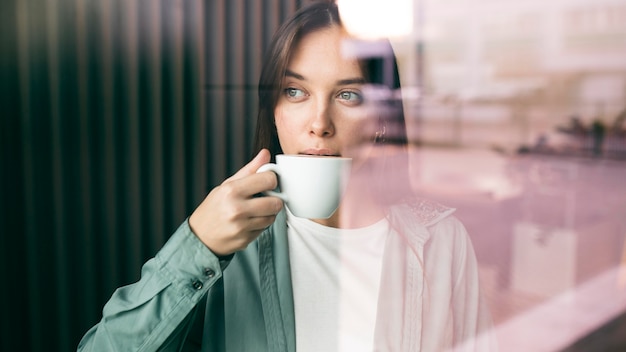 Portret van een jonge vrouw die van koffie geniet
