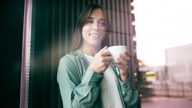 Portret van een jonge vrouw die van koffie geniet