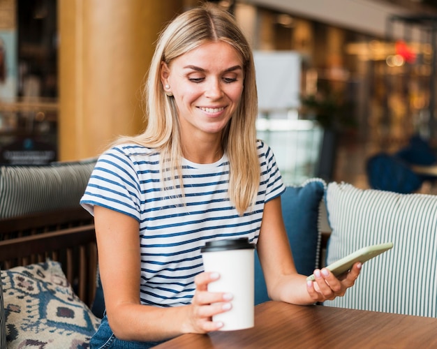 Gratis foto portret van een jonge vrouw die van koffiekop geniet