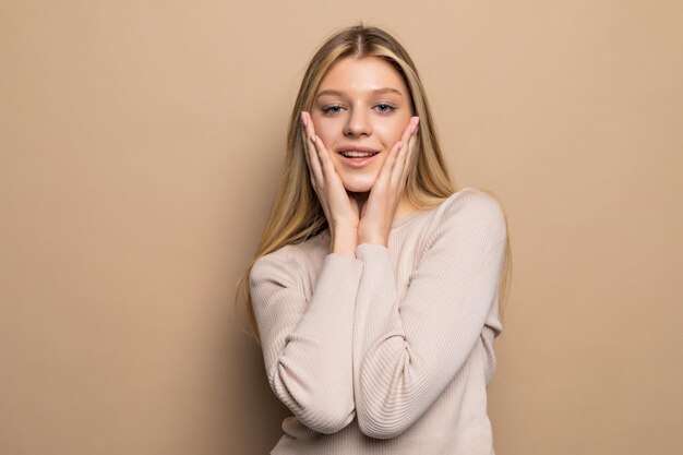 Portret van een jonge vrouw die verrast kijkt op een beige muur