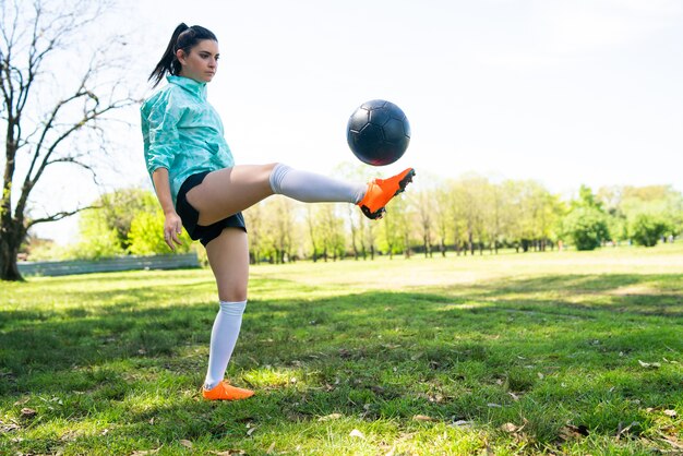 Portret van een jonge vrouw die voetbalvaardigheden oefent en trucs doet met de voetbalbal