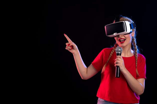 Portret van een jonge vrouw die vr speelt en met microfoon zingt op donkere visuele gamemuziek