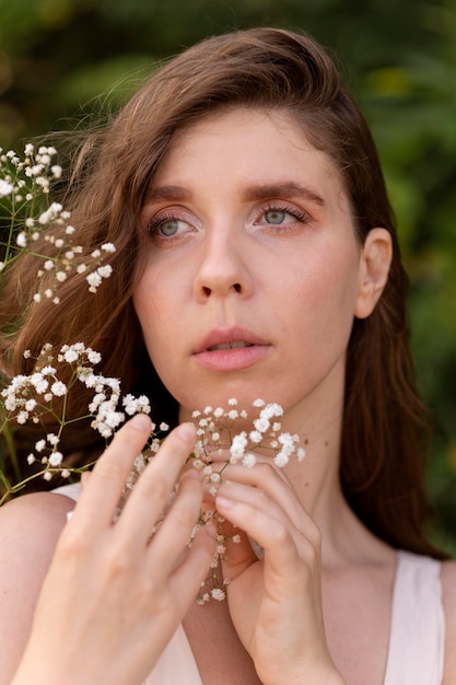 Portret van een jonge vrouw die zelfverzekerd buiten poseert met bloemen