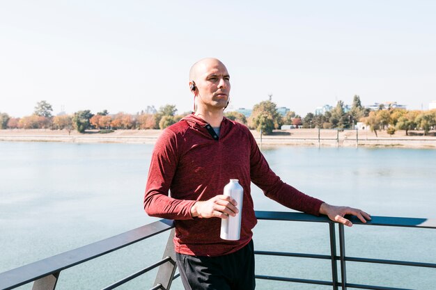 Portret van een jonge vrouw die zich dichtbij de fles van het meerholdingswater in hand bevindt