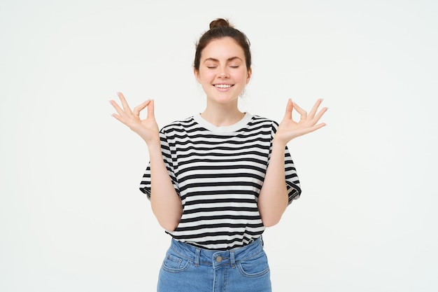 Gratis foto portret van een jonge vrouw die zich ontspant, zen voelt, mediteert, glimlacht met een tevreden, rustige gezichtsuitdrukking.