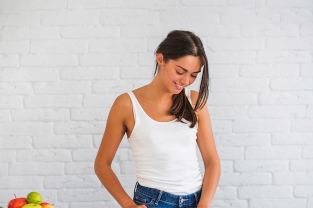 Portret van een jonge vrouw die zich tegen witte bakstenen muur