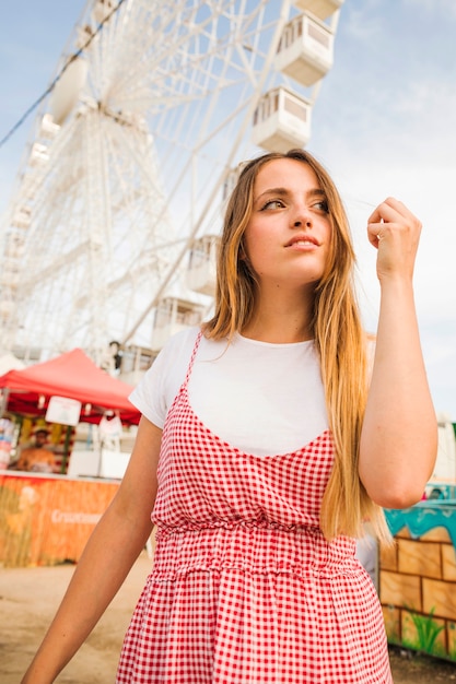 Portret van een jonge vrouw die zich voor reuzeferriswiel bevindt